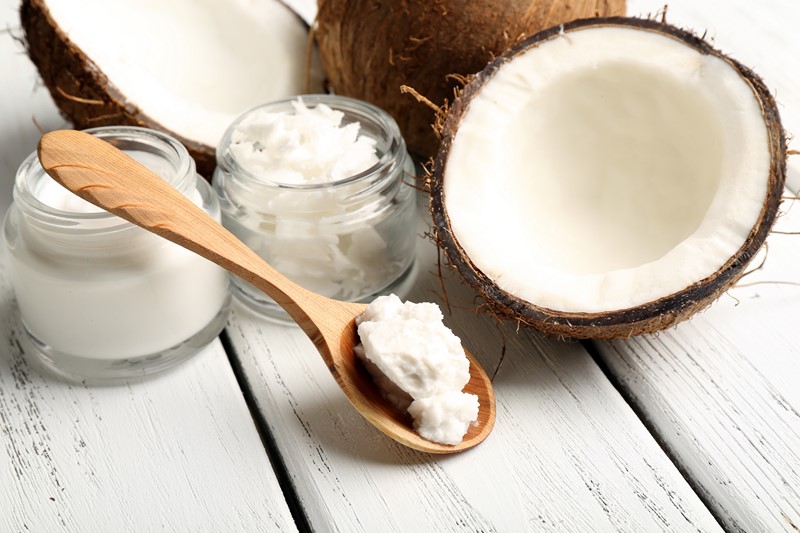 Coconut with jars of coconut oil and cosmetic cream on wooden background Жиры – польза и вред